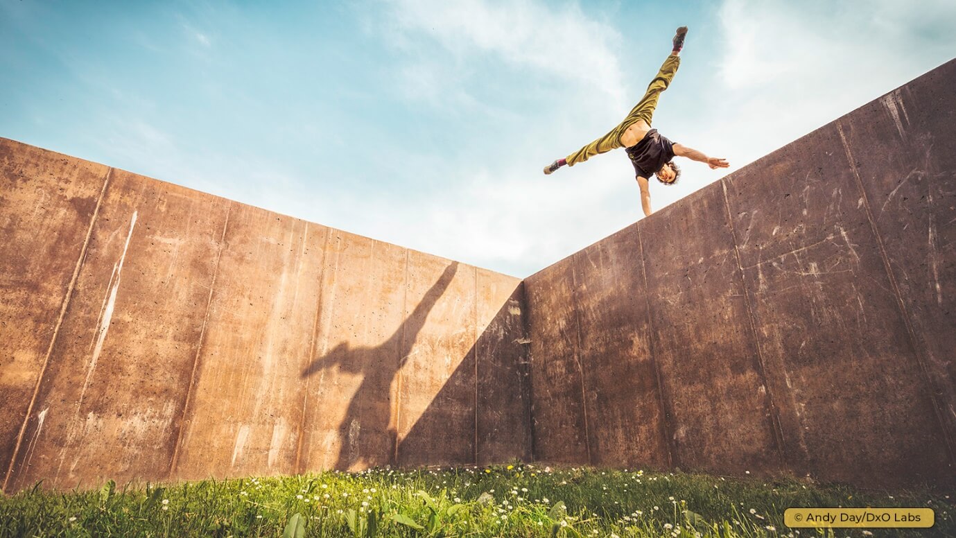 A person doing a hand flip on a wall Description automatically generated